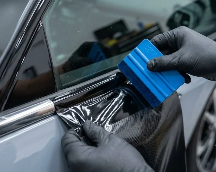 Vinyl wrap installation close-up — heat gun technique and edge tucking for chrome delete