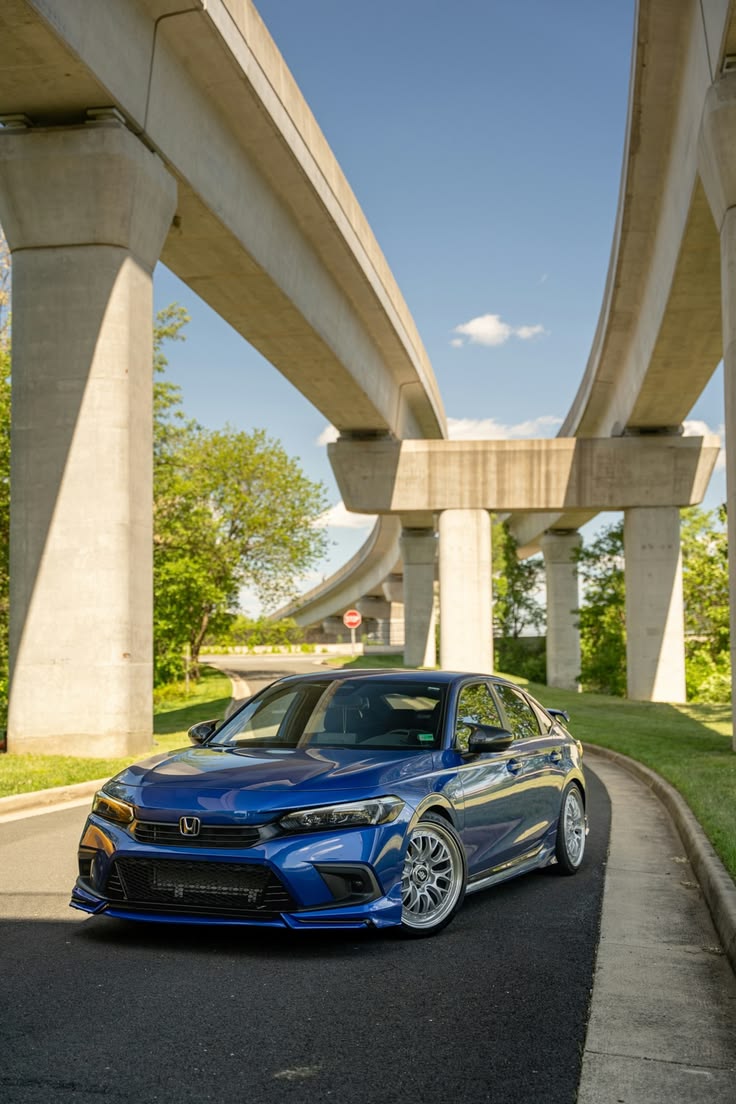 Modified blue Honda Civic 11th gen parked under concrete highway overpass